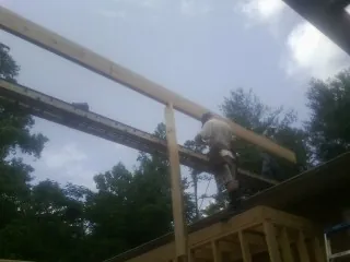Carpenter setting a ridge beam over a new addition frame — Ice Dam Removal by Roofing Brothers in Serena