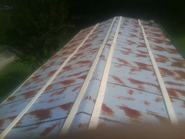 Rusted metal roof panels with new wood purlins before replacement — Storm Damage Roof Repair in Serena by Roofing Brothers