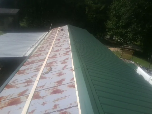 Old rusted panels beside newly installed green metal roofing — Wind Damage Roof Repair by Roofing Brothers in Serena