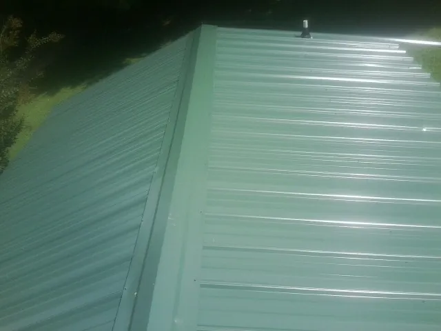 New green metal panels meeting at the ridge of a roof — Flat Roof Repair work by our crew in Serena