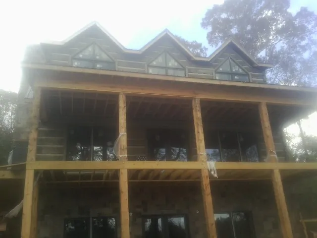 Dormers and porch framing on a large log home under construction — Roof Coating work by our crew in Serena