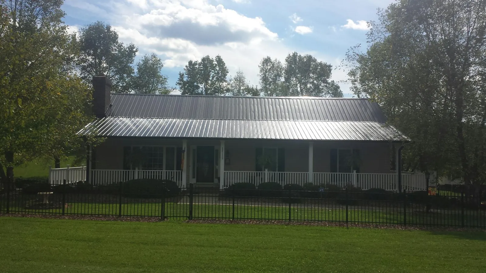 Gray metal roof on a brick ranch with a full width front porch — Gutter Guard Installation work by our crew in Serena