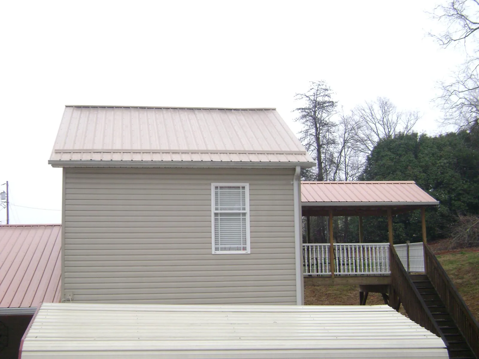 Tan metal roofs on a two story addition and attached porch, from a Roof Replacement job in Serena